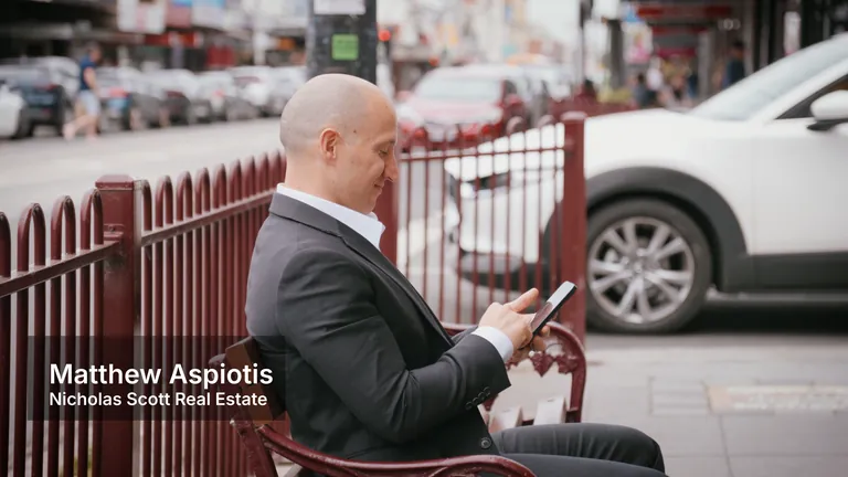 Matthew Aspiotis from Nicholas Scott Real Estate using his phone outside